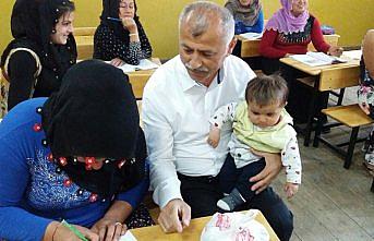Kucağında çocuklarıyla okuma yazma öğreniyorlar